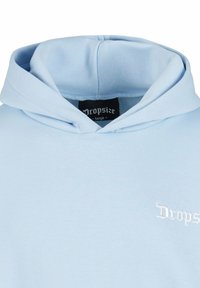 Sweat à capuche bleu clair avec capuche pliée et étiquette "Dropsize" à l'intérieur du col ainsi qu'un petit logo brodé blanc "Dropsize" sur la poitrine.