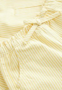 Tissu rayé jaune avec des lignes blanches, doté d'une taille élastique et d'un détail nœud, texture douce, et une poche sur le côté.