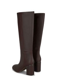 Bottes en cuir bordeaux montant jusqu'aux genoux, avec une texture lisse, un embout carré et un talon épais ; finition minimaliste et design élancé.