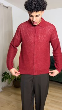 Cardigan rosso in maglia con colletto, chiusura con bottoni e motivi a punto visibili, indossato sopra pantaloni scuri. Leggero e dalla vestibilità rilassata.