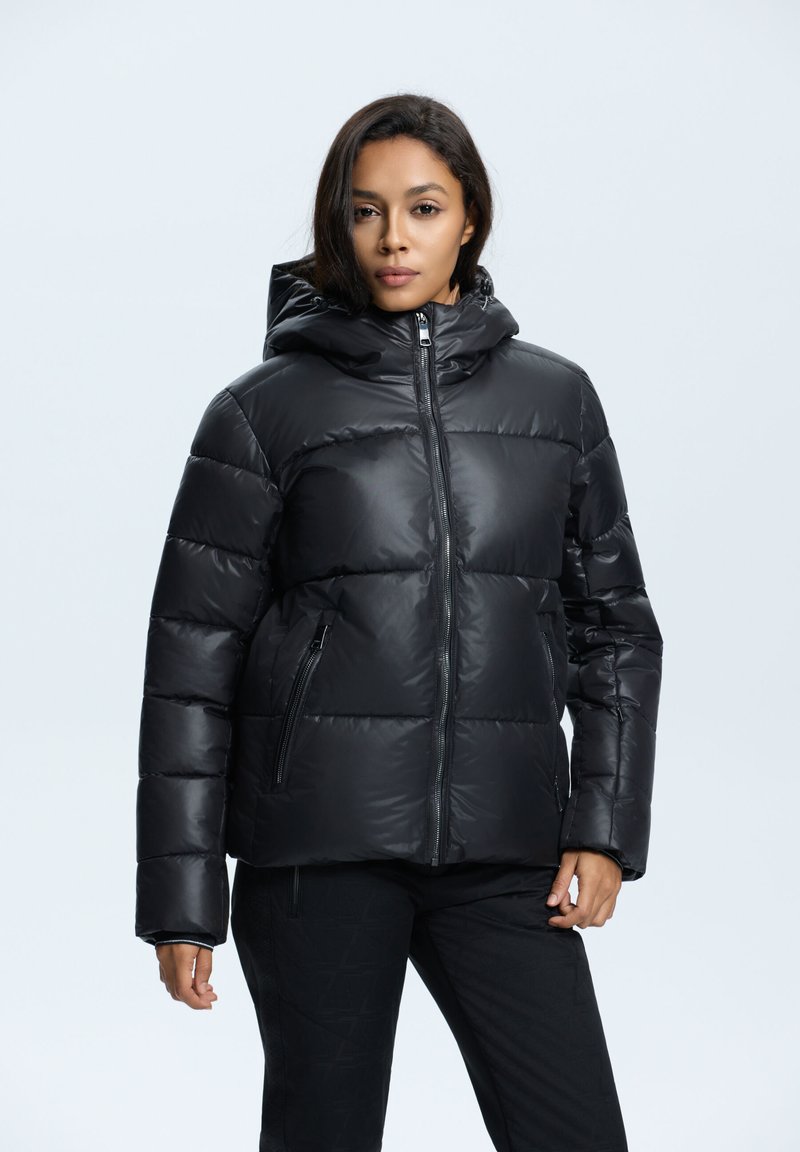 Chaqueta de plumas negra con capucha, con cierre de cremallera frontal, puños elásticos y dos bolsillos laterales con cremallera. Acabado liso y brillante con secciones acolchadas.