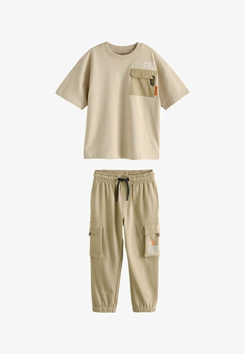 Beżowa bawełniana koszulka z kieszonką z przodu i napisem. Pasujące beżowe spodnie mają elastyczny pas, sznurek oraz dwie boczne kieszenie cargo.