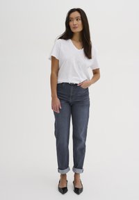 T-shirt bianco con scollatura a V abbinato a jeans blu scuro con risvolti e ballerine nere a punta. Design semplice con una texture morbida.