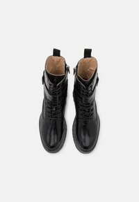 Zwarte leren enkelboots met een gladde afwerking, vetersluiting aan de voorkant, zijritsen en een gestructureerde rubberen zool. Het interieur is voorzien van een tan kleurig binnenwerk.