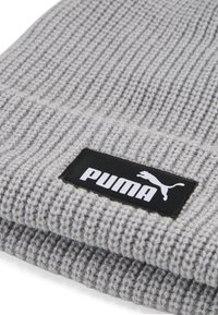 Grå strikket beanie med ribbet tekstur, der har et sort rektangulært mærke med den hvide "PUMA"-logo og et springende puma-design.