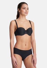 Black padded bra with scalloped strap detail. Smooth fabric, underwire design, matching black bikini bottom with a simple, low-rise cut.
