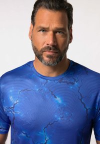 Modré krátkosrsté sportovní tričko s grafickým vzorem a tmavšími bleskovými liniemi a texturovaným povrchem. Design s kulatým výstřihem.