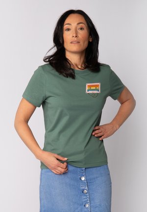 Groene katoenen t-shirt met een cassetteafbeelding in rood, geel en blauw op de borst, ronde halslijn en korte mouwen.