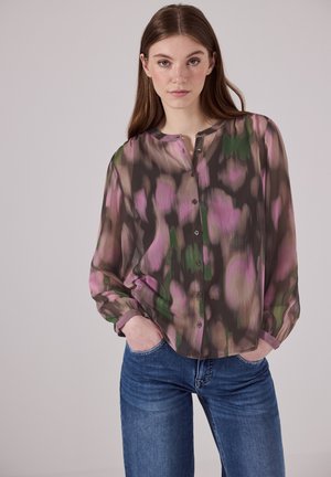 Blusa trasparente con bottoni, caratterizzata da un motivo astratto nei toni del rosa, verde e marrone. Presenta un collo rotondo e maniche lunghe. Abbinata a jeans blu.