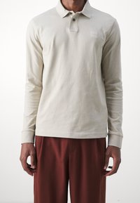 Lange mouwen polo in lichtbeige katoen, met een drie-knopen sluiting, geribde mouwen en een klein logo op de borst.