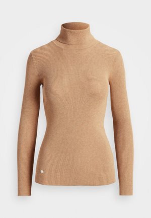 Pull en maille côtelée couleur camel avec col roulé, aux manches longues et une petite étiquette en métal près de l'ourlet, sur fond blanc.