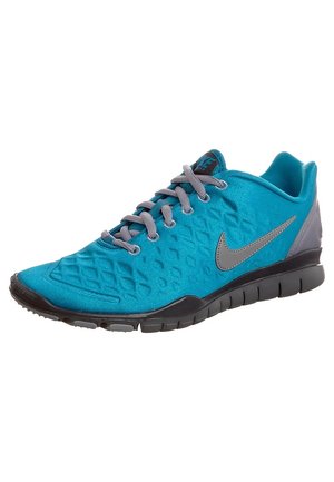 Chaussure de course Nike bleue avec lacets gris, logo Nike gris, tige texturée et semelle noire flexible inclinée vers la droite.