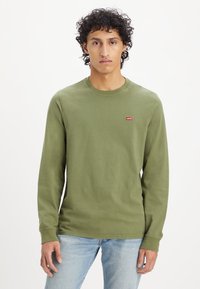 Olive zöld, hosszú ujjú pamut ing, kerek nyakkivágással és egy kis piros Levi's logóval a mellkasán. Kényelmes fazon.