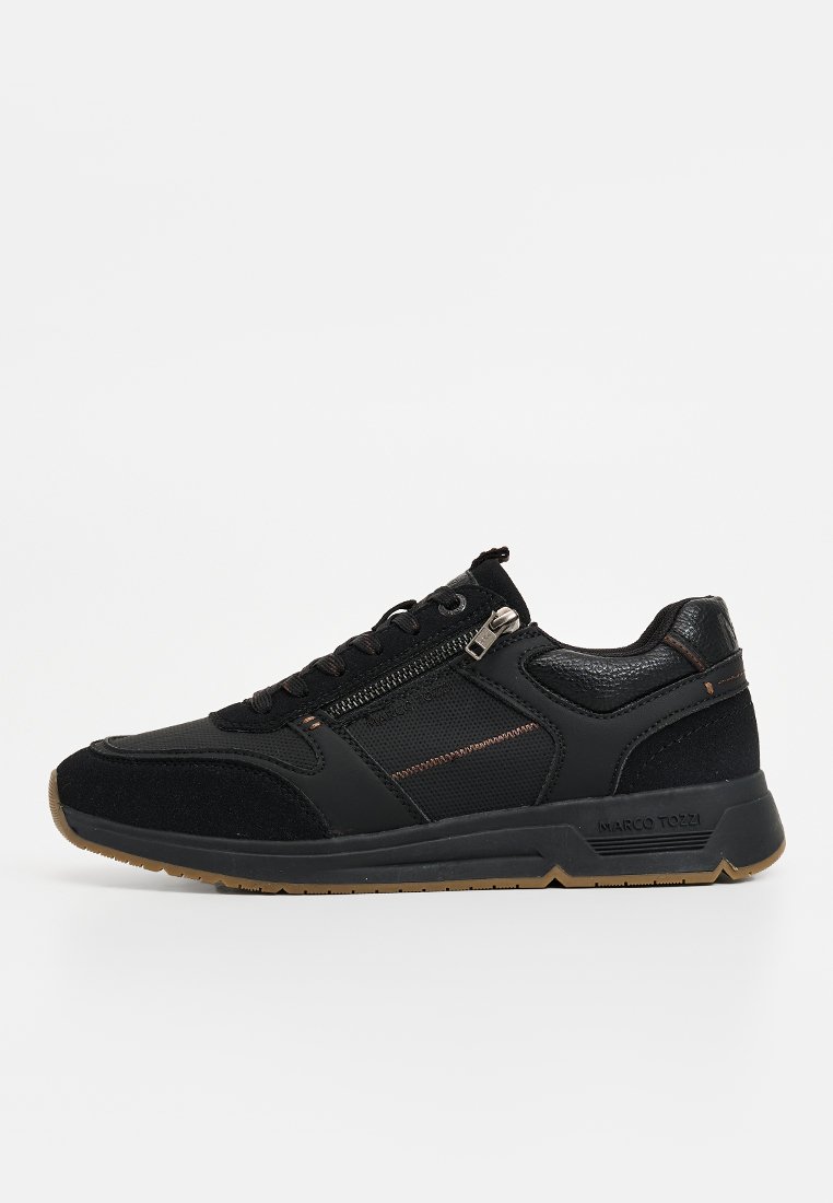 Baskets noires avec un mélange de suede et de mesh, un dessus texturé, des accents en bronze subtils et une fermeture éclair sur le côté pour un enfilage facile.