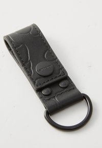 Fekete bőr kulcstartó szíj dombornyomott mintával, patent gombokkal és kör alakú fém gyűrűvel a rögzítéshez. Sima felület, téglalap alakú.