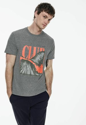 Grå bomulds T-shirt med korte ærmer, der har et stort grafisk design i orange og sort, som står "CLUB" på en tekstureret baggrund.