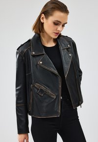 Giacca da motociclista nera in pelle con cerniera frontale, bottoni a pressione e dettagli in una pelle dalla texture più chiara; design slim fit.