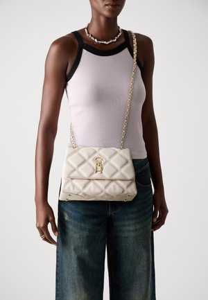 Quilted cream handbag with gold hardware, chain strap, and logo detail. Features a rectangular shape and smooth texture. Worn crossbody.
