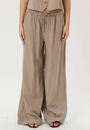 Beige vidbenede linnedbukser med elastisk talje og bindebånd, båret med en matchende cropped top med knapper og åbne sandaler.