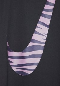 Czarny t-shirt z materiału z dużym różowym i fioletowym paskowanym logo Nike swoosh. Gładka tekstura z żywymi kontrastującymi kolorami.