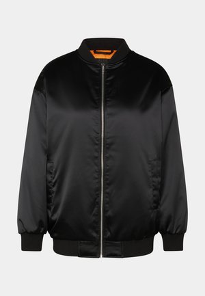 Svart bomberjakke laget av glatt satin, med glidelås foran, ribbestrikkede mansjetter og hem, og oransje fôr. Klassisk og minimalistisk design.