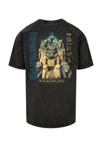 Sort bomulds t-shirt med et grafisk design, der indeholder egyptisk-inspirerede motiver og teksten "Iron Maiden PowerSlave" i blå og guld.