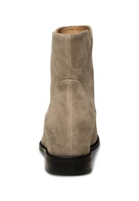 Beige mockasnörsko med rund tå och en slät svart klack. Inuti �är den klädd med ljusläder.