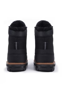 Schwarze Winterstiefel mit einem weichen, mit Fell gefütterten Kragen, strukturierten Seiten und einer robusten Gummisohle mit einem braunen Akzentstreifen.