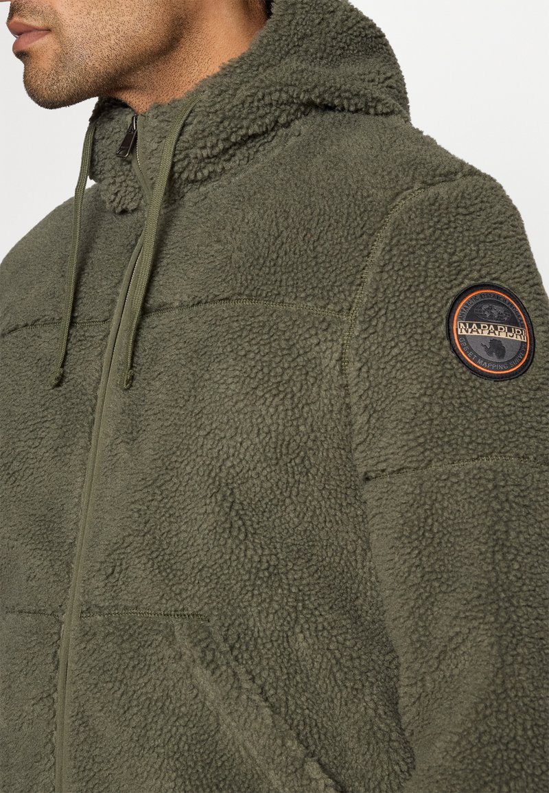 Mann in grüner Fleecejacke mit Reißverschluss und Kapuze, mit Napapijri-Logo-Patch auf dem oberen Arm.