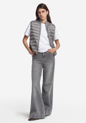 Grå puffervest med en quiltet tekstur, båret over en hvid T-shirt og parret med vide grå jeans. Casual stil med et enkelt design.