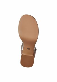 Soletta sintetica tan con superficie testurizzata, forma arrotondata e tacco leggero. Presenta un accento metallico vicino al punto di attacco della fascia.