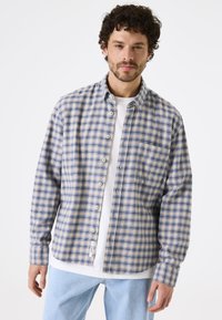 Geruite shirt met blauwe, gele en crèmekleurige vierkanten, knoopsluiting aan de voorkant, verspreide kraag, lange mouwen en een borstzak. Zachte stoftextuur.