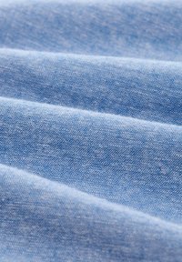 Tela azul claro con una textura suave, que presenta patrones de tejido sutiles y capas plegadas, resaltando su suavidad y ligereza.