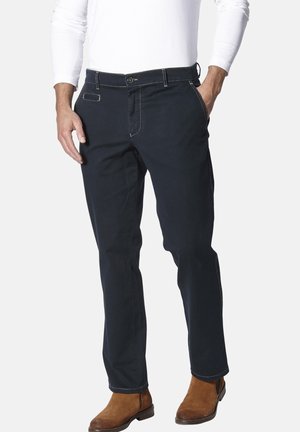 Herren Dunkelblaue Baumwollhose. Merkmale: gerader Schnitt, fünf Taschen und kontrastierende Nähte. Getragen mit braunen Stiefeln.