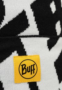 Black and white knitted beanie featuring a geometric pattern. Includes a bright yellow rectangular tag with "Buff" logo.