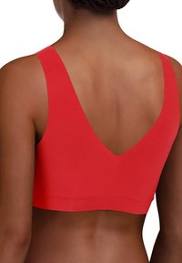 Roter Sport-BH mit breiten Trägern und tiefem V-Ausschnitt-Design. Hergestellt aus glattem Stoff, verfügt er über eine nahtlose, enganliegende Silhouette.