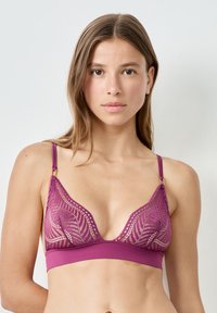 Bralette en dentelle de couleur violet profond, avec une forme triangulaire, des détails en dentelle transparente et des bretelles réglables avec des accessoires en métal doré.