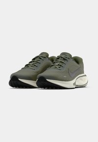 Ανδρικά παπούτσια Nike για τρέξιμο, πάνω μέρος από πράσινο ύφασμα, α νοιχτό γκρι σήμα Swoosh, μαξιλαρωμένη λευκή σόλα, υφή επιφάνειας, μαύρη καουτσούκ εξωτερική σόλα, στρογγυλή μύτη.