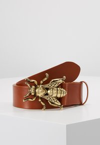 Brown leather belt with a large, detailed golden bee-shaped buckle. Smooth texture, wide strap, and an adjustable clasp.