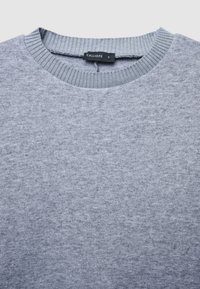 Grauer Pullover mit Rundhalsausschnitt und geripptem Kragen, hergestellt aus einem strukturierten Stoff. Verfügt über ein Markenetikett im Krageninneren.