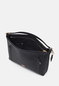 Czarna skórzana torebka na ramię z złotym zamkiem błyskawicznym i emblematem, z jedną główną komorą częściowo otwartą, zawierającą wewnętrzną kieszeń na zamek i pojedynczy pasek.