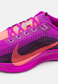 Nike Pegasus løbesko med en strikket overdel i nuancer af lilla og pink, et sort og orange swoosh og en polstret lilla sål.