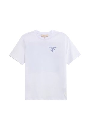 T-shirt blanc à manches courtes avec petit texte bleu “GERTRUDE” et emblème en forme de croix sur le haut gauche de la poitrine, col rond.