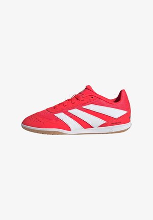 Zapatillas deportivas rojas con rayas blancas, parte superior de malla, suela de goma, cuello acolchado y puntera redonda. Presenta detalles perforados en la parte delantera.