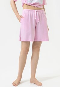 Lichtroze katoenen shorts met een elastische tailleband, verstelbaar trekkoord en zijzakken. Heeft een relaxte pasvorm met splitten aan de zijkanten.