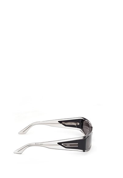 Gafas de sol transparentes con acentos gruesos en negro y la marca "GCDS" en las patillas, mostradas desde un ángulo lateral sobre un fondo blanco.
