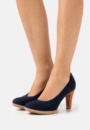 Chaussures à talons hauts en velours bleu marine avec bout arrondi, plateforme imitant le bois naturel et accent orange vif sur le talon.