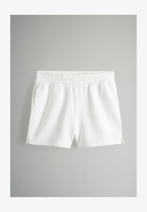 Vita bomullsshorts med elastisk midja, sidofickor och slitsar på fållen. Slät textur och avslappnad design.