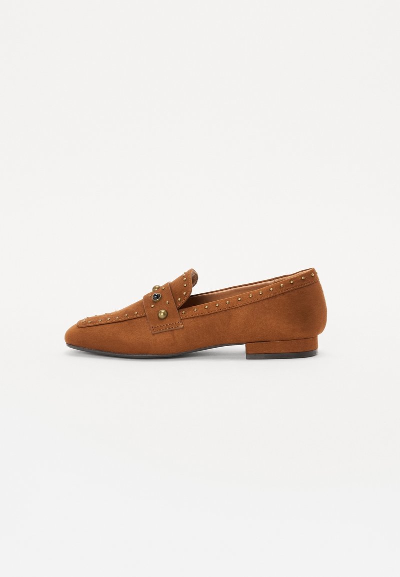Mocassins en suede marron avec un bout pointu, ornés de clous en or décoratifs et d'une lanière avec des accents métalliques. Talon bas et texture lisse.