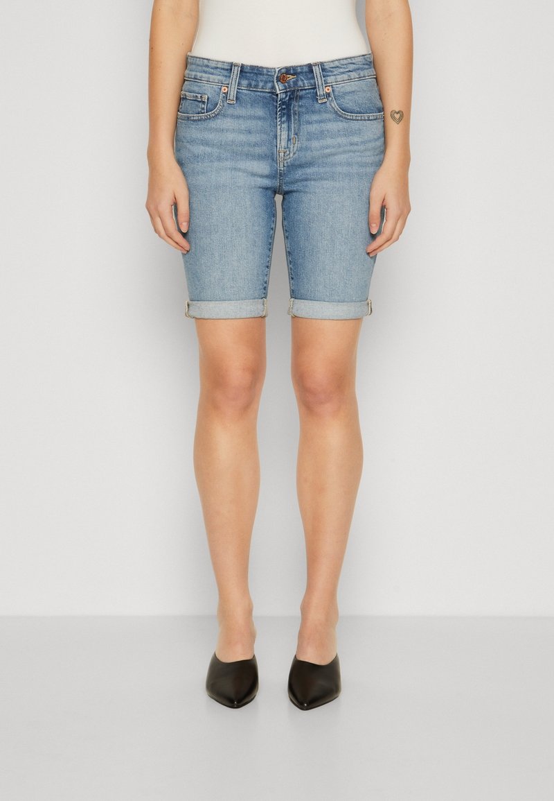 Vaaleansiniset farkkushortsit, joissa on käännetyt lahkeet, viiden taskun malli ja istuva siluetti. Yhdistetty mustiin, teräväkärkisiin kenkiin.